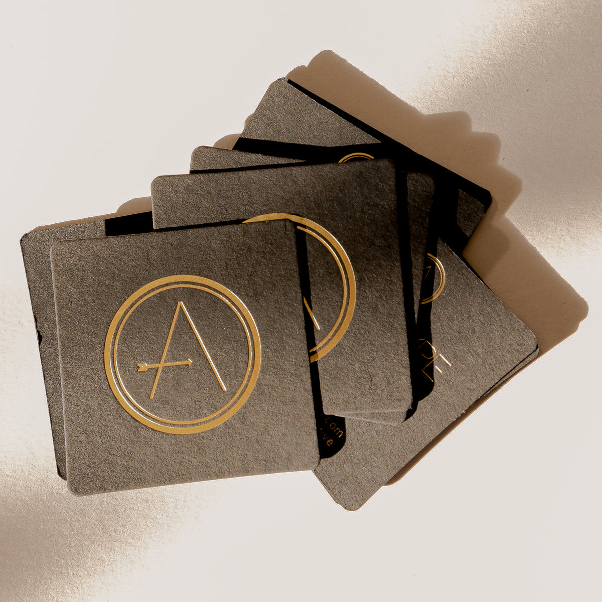 Set of black cards with gold circular design and letter 'A' on a light background