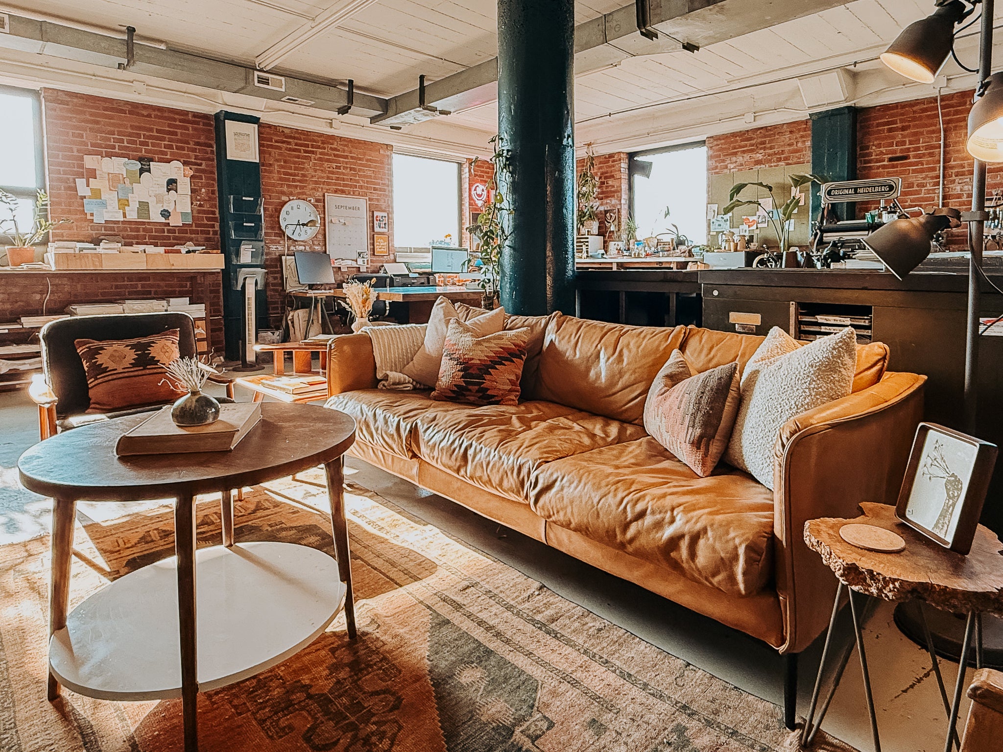 Public Print Studio Space with leather couch and brick walls. Letterpress machine in background. 
