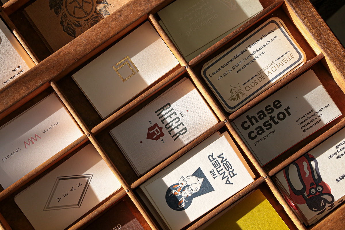 Collection of business cards in a wooden box with various designs and text.