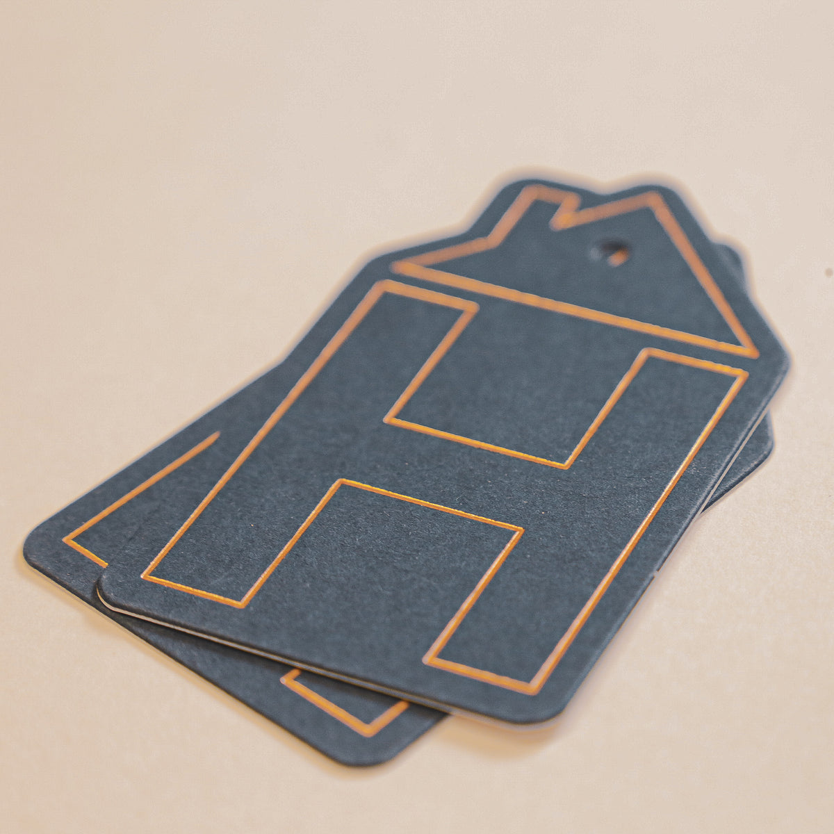 Two blue paper tags with gold outlines on a beige background