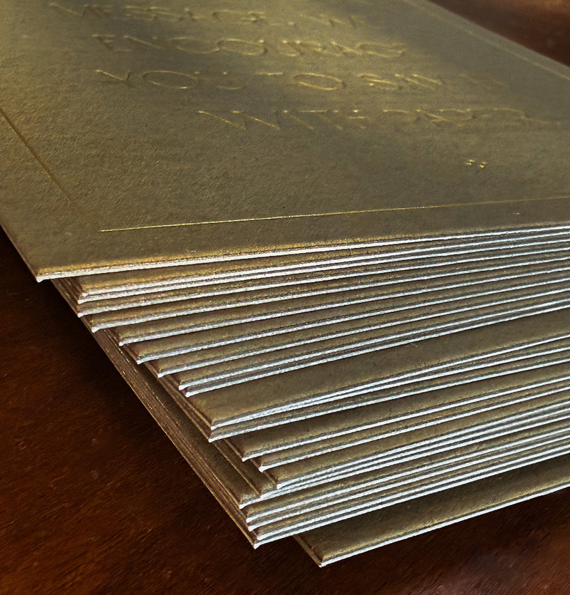 Stack of gold foiled cards on a wooden surface that are duplexed