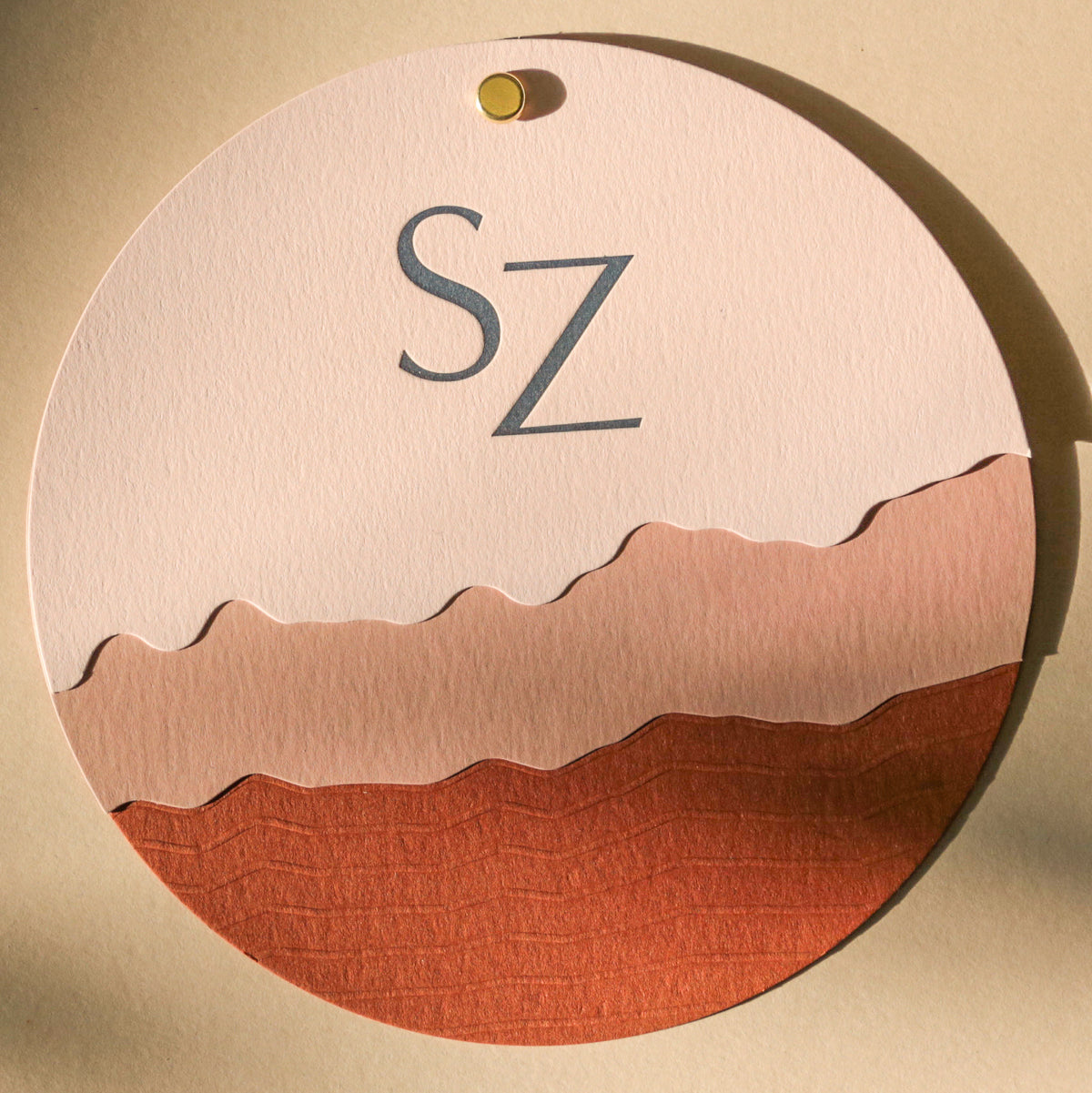 Round decorative item with 'SZ' initials on a beige background