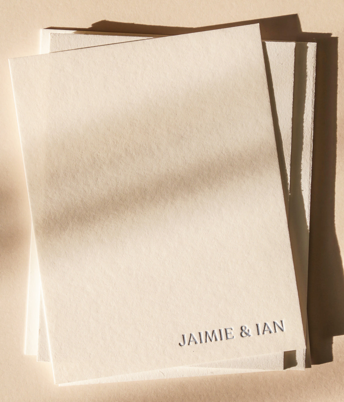 Stack of white cards with names against a beige background