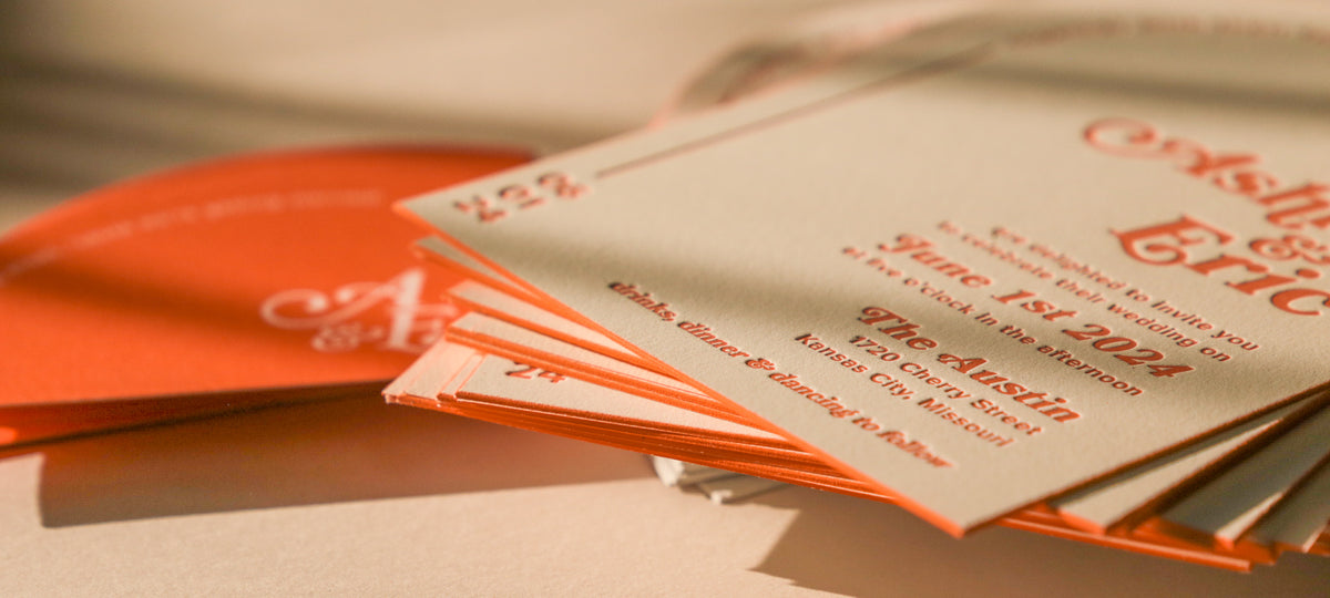 Stack of orange and white invitations on a textured surface
