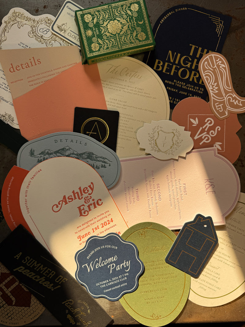 Collection of various wedding invitations and stationery items on a wooden surface.