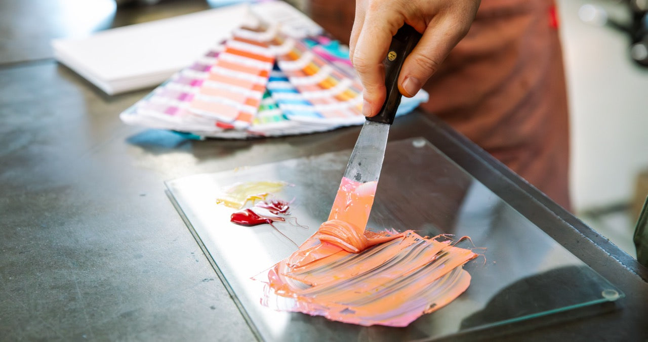 Person mixing letterpress ink with Pantone swatch book in background.
Photo by Alyssa Broadus