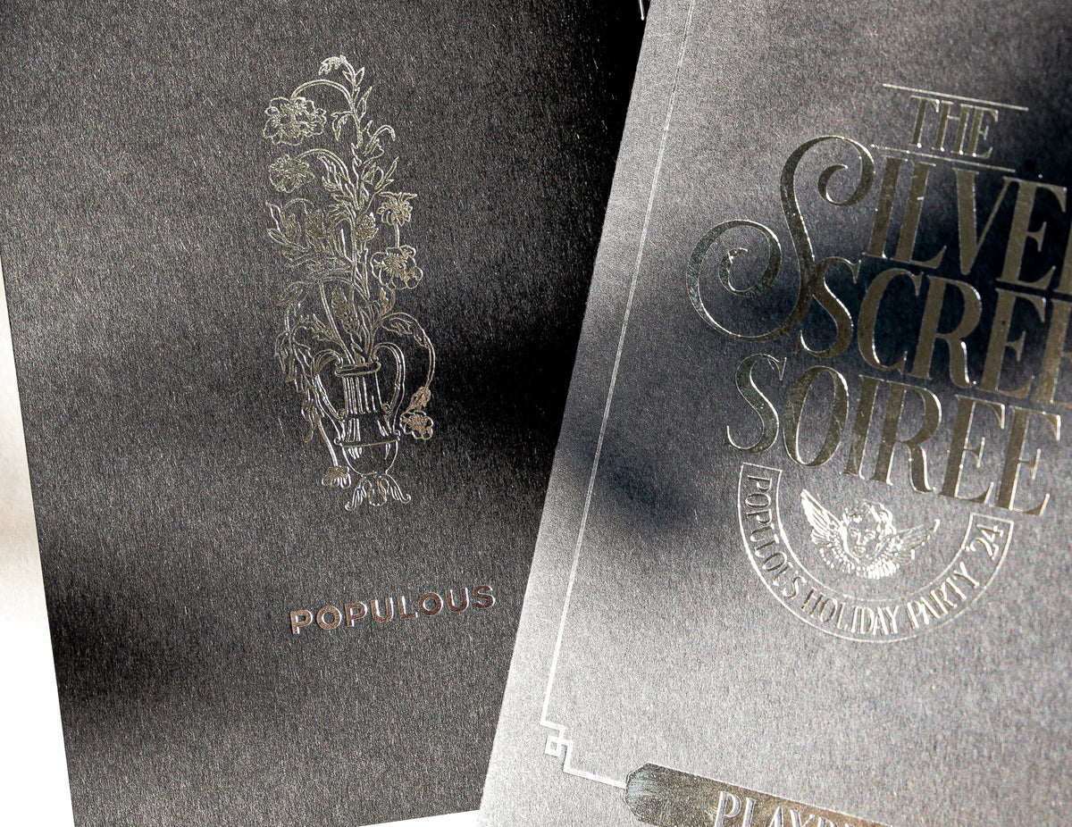 Two black books with silver foil text and designs on a black background